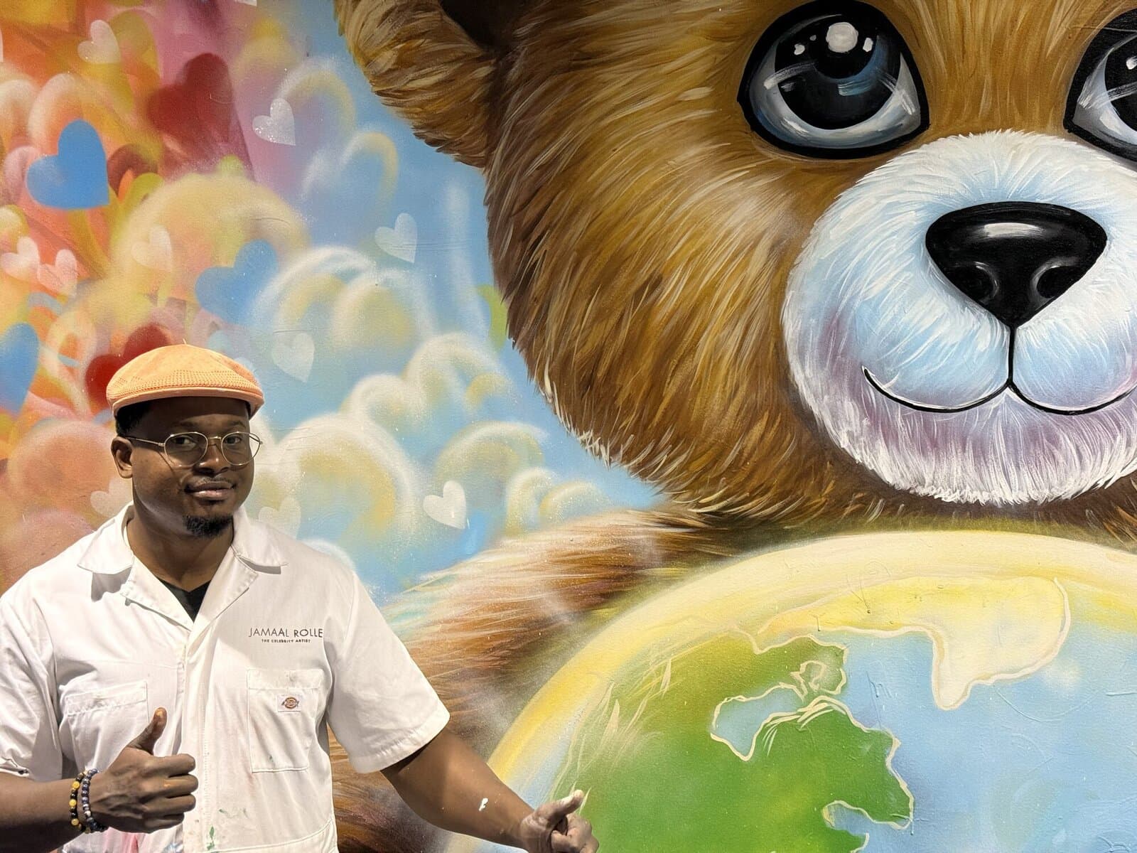 Jamaal Rolle giving a thumbs up beside his finished teddy bear mural.