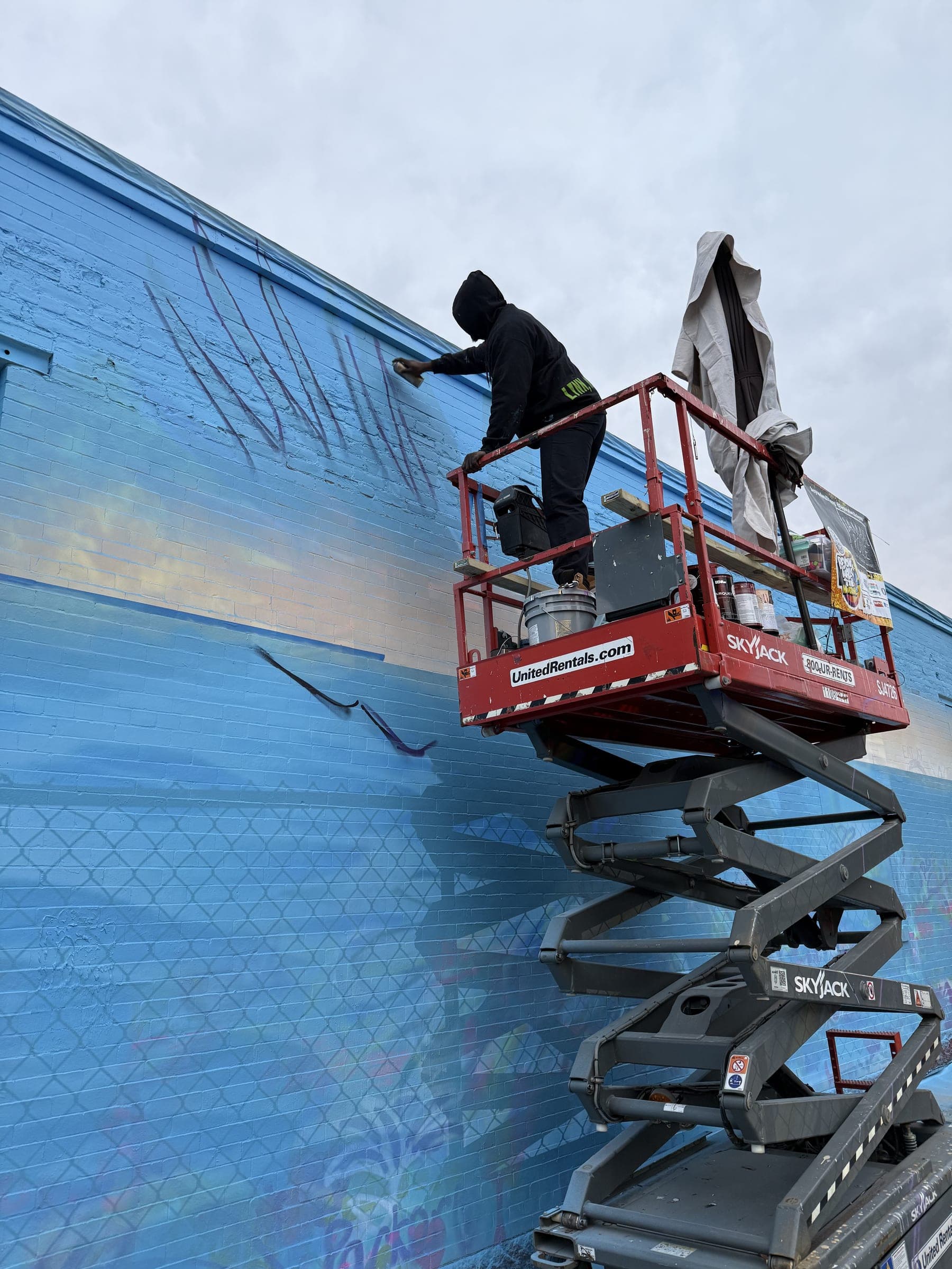 Jamaal Rolle on a lift, painting the eagle mural four storeys up.