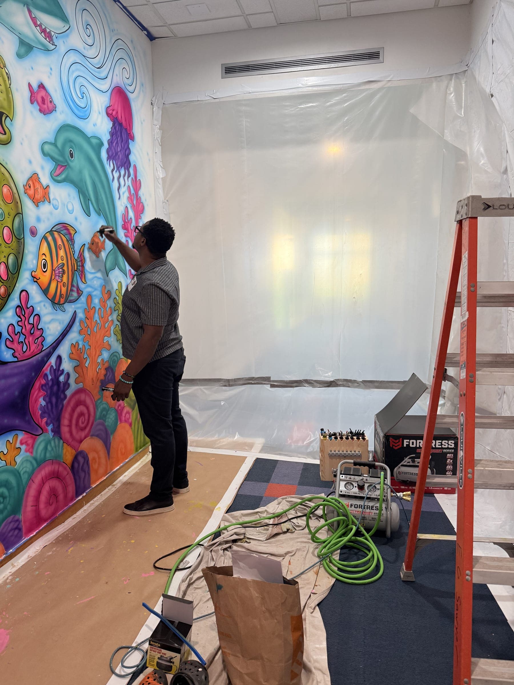 A young painter adding colour to the mural outlines