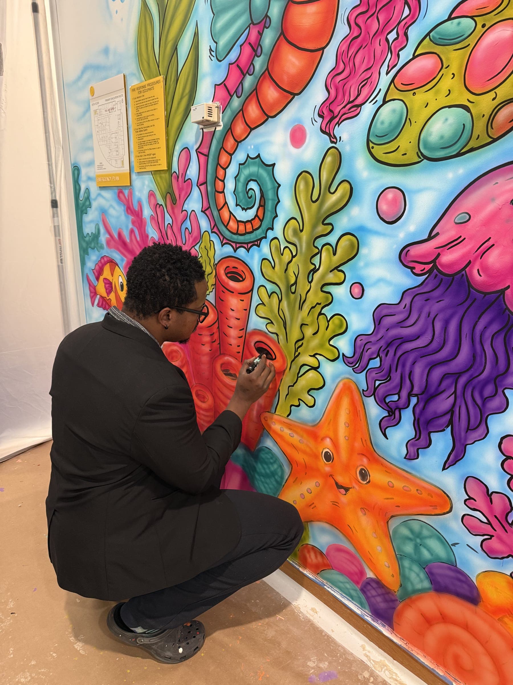 Jamaal painting alongside young painters at the seahorse wall